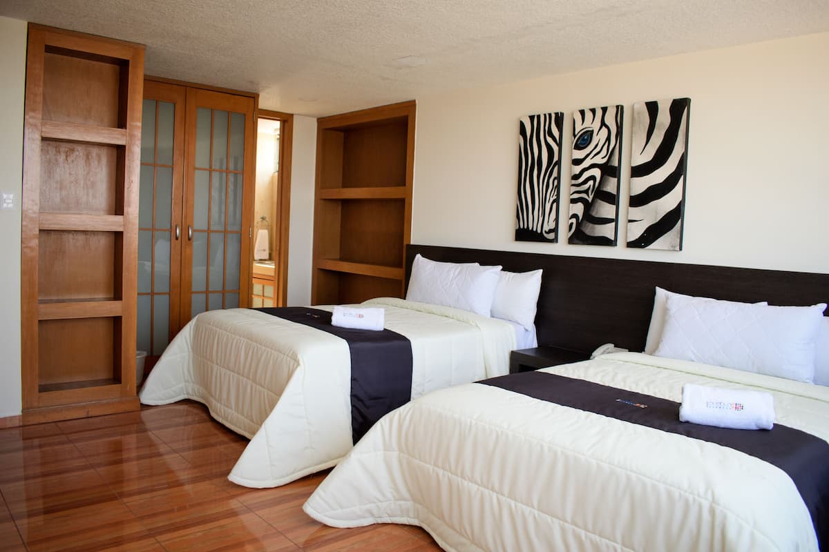 Habitación de hotel con dos camas, armario de madera y una obra de arte en la pared.