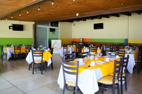 A restaurant with multiple tables set for dining, featuring yellow tablecloths and wooden chairs. - Puebla Inn Express (Puebla)