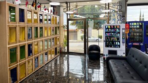 Un hall de hotel con una recepción, una zona de estar, máquinas expendedoras y una exhibición de banderas.