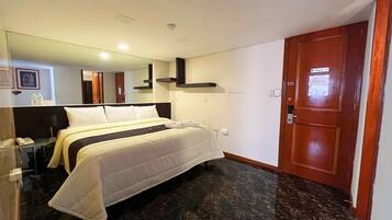 Habitación de hotel con cama, puerta de madera, espejo y suelo de mármol.