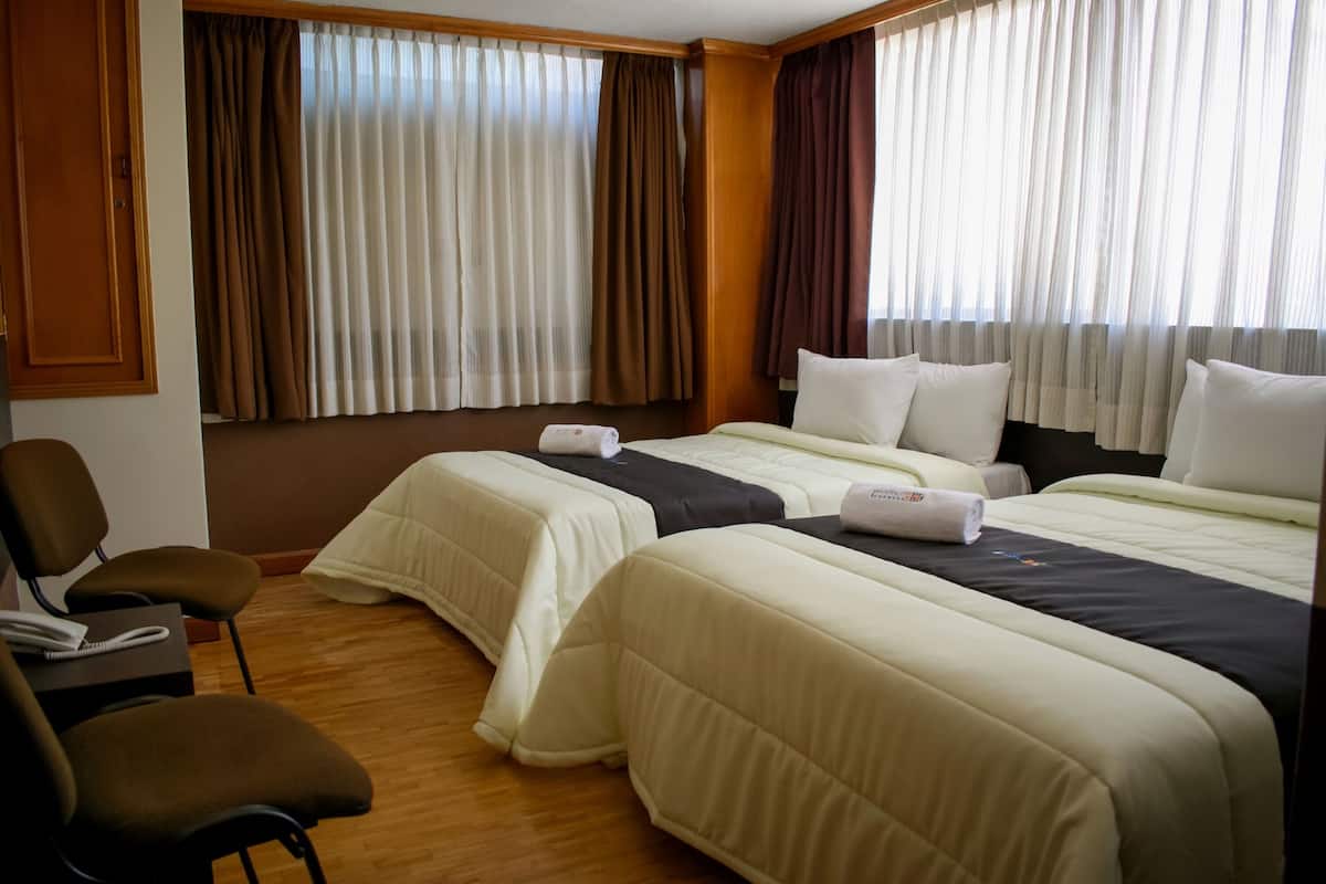 Habitación de hotel con dos camas, un escritorio con teléfono y una silla.