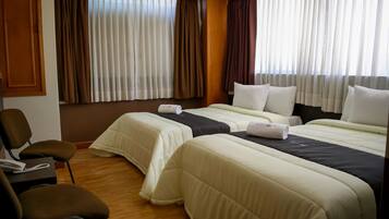 A hotel room with two beds, a desk with a telephone, and a chair.