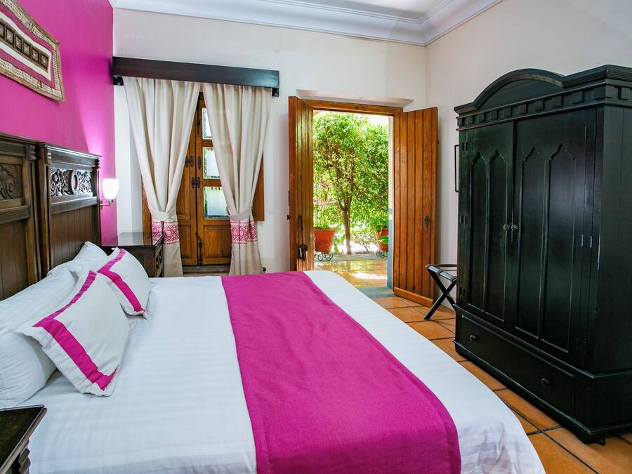 Una habitació d'hotel amb un llit, un armari i vistes a l'exterior.