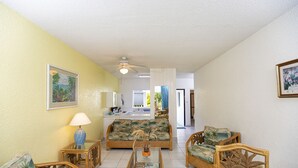 Una sala de estar con sofá, sillones, mesa de centro y televisor.