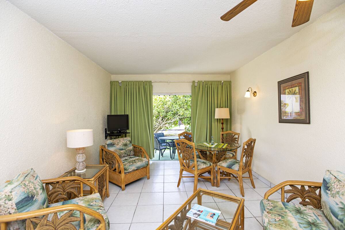 A room with wicker furniture, a television, and a dining table with chairs.