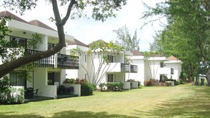 Una hilera de edificios modernos y blancos con balcones, rodeados de céspedes y árboles bien cuidados.
