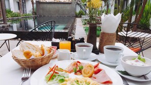 Ein Frühstückstisch mit Rührei, Schinken und Gemüse, dazu Brot, Kaffee und Saft.