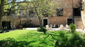 A courtyard with a stone building, outdoor seating, and a tree. - Finca Hotel Son Pont (Puigpunyent)