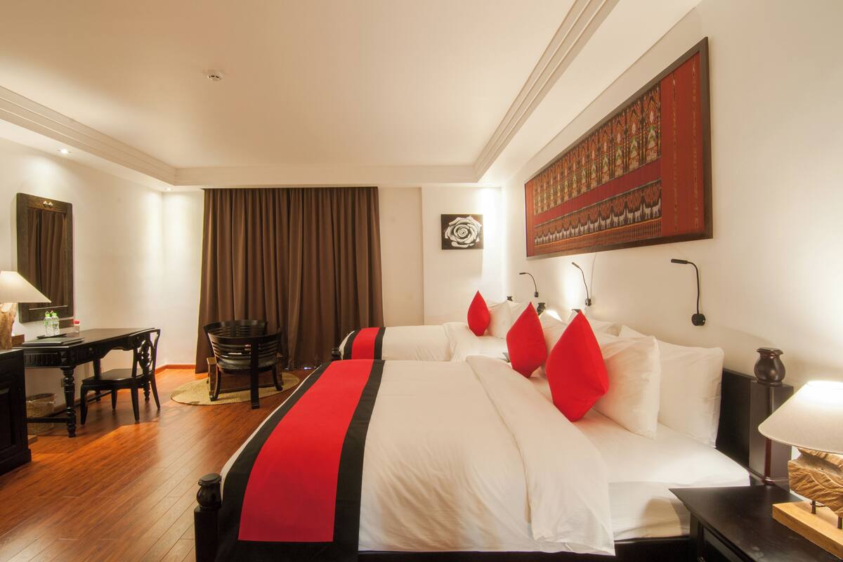 Habitación de hotel con dos camas, un escritorio, una silla y un cuadro grande en la pared.