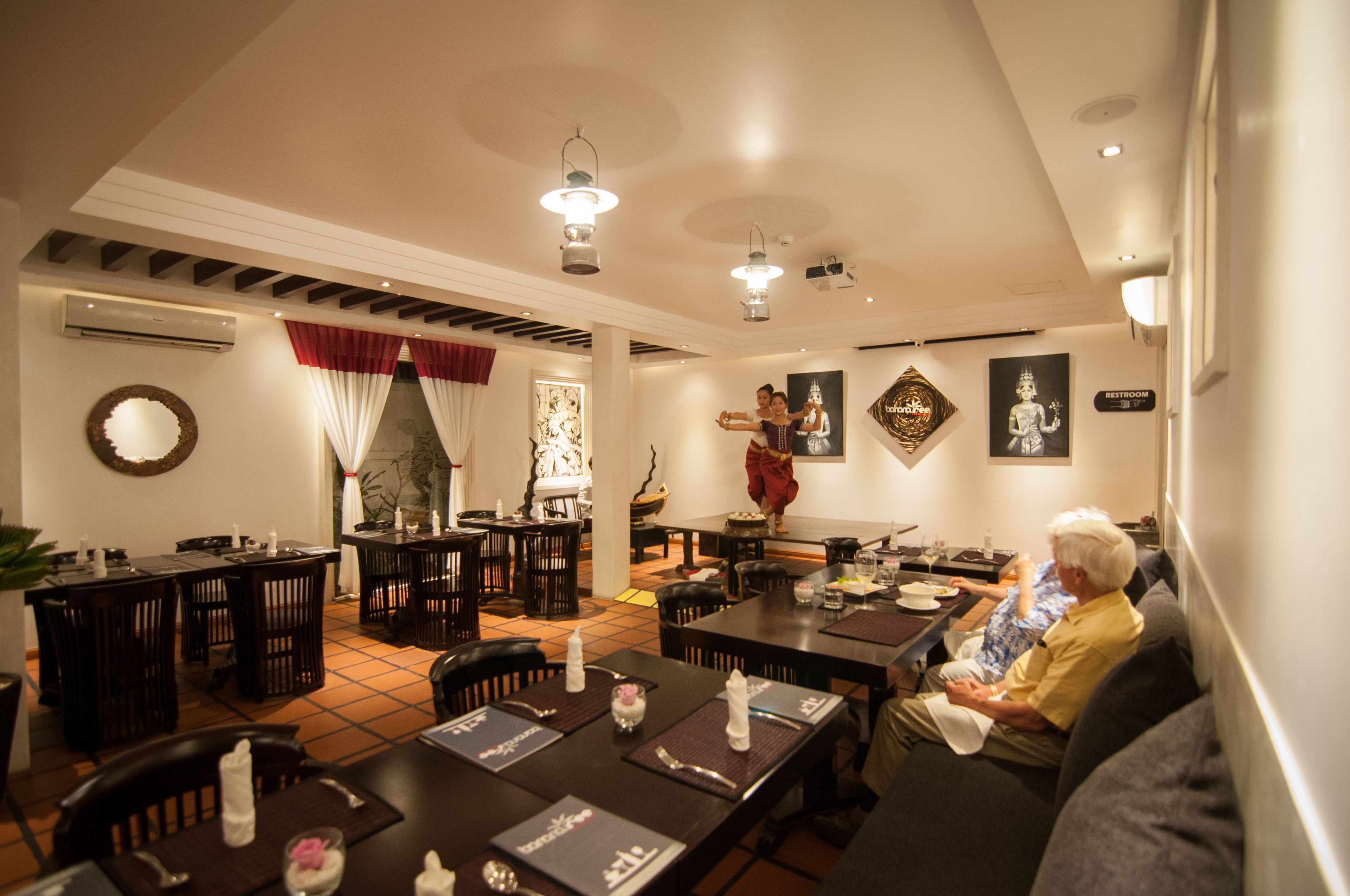A dining area with multiple tables and chairs, an air conditioning unit, and a staircase leading to an upper level.