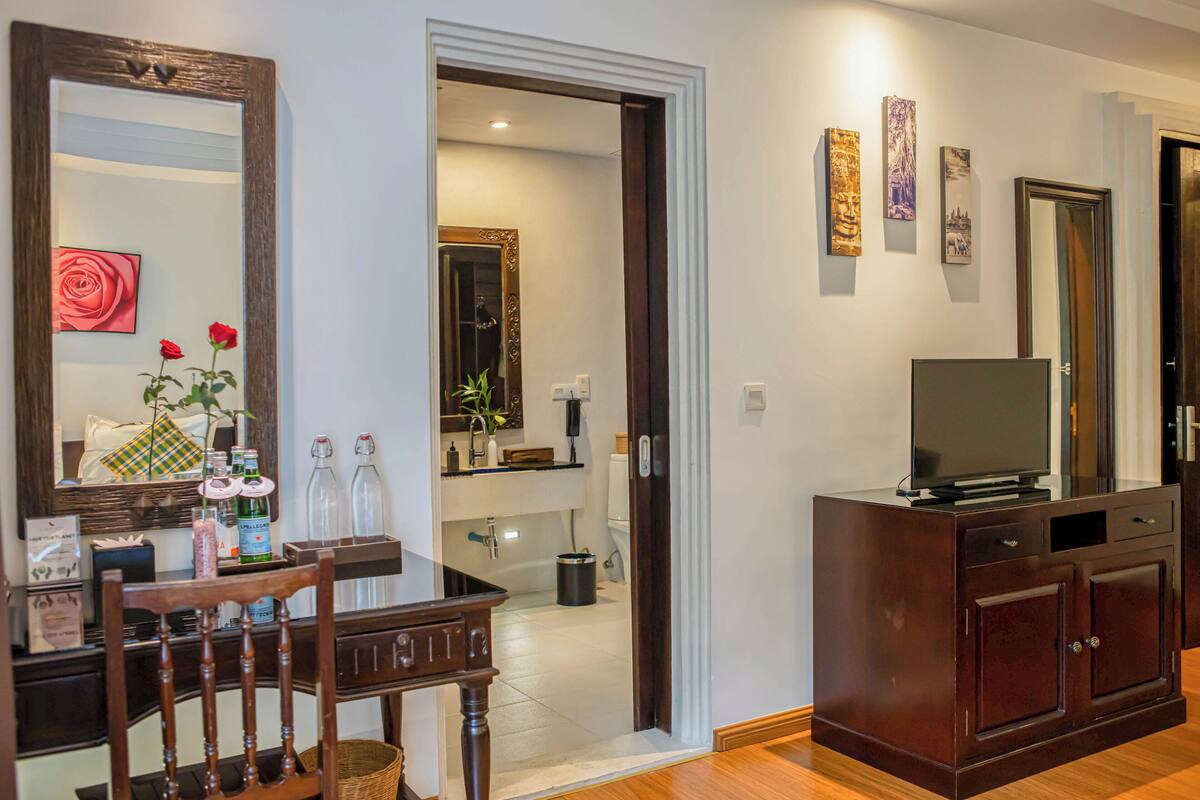 Una sala de estar con un mueble de madera, un televisor y una mesa de comedor con sillas.