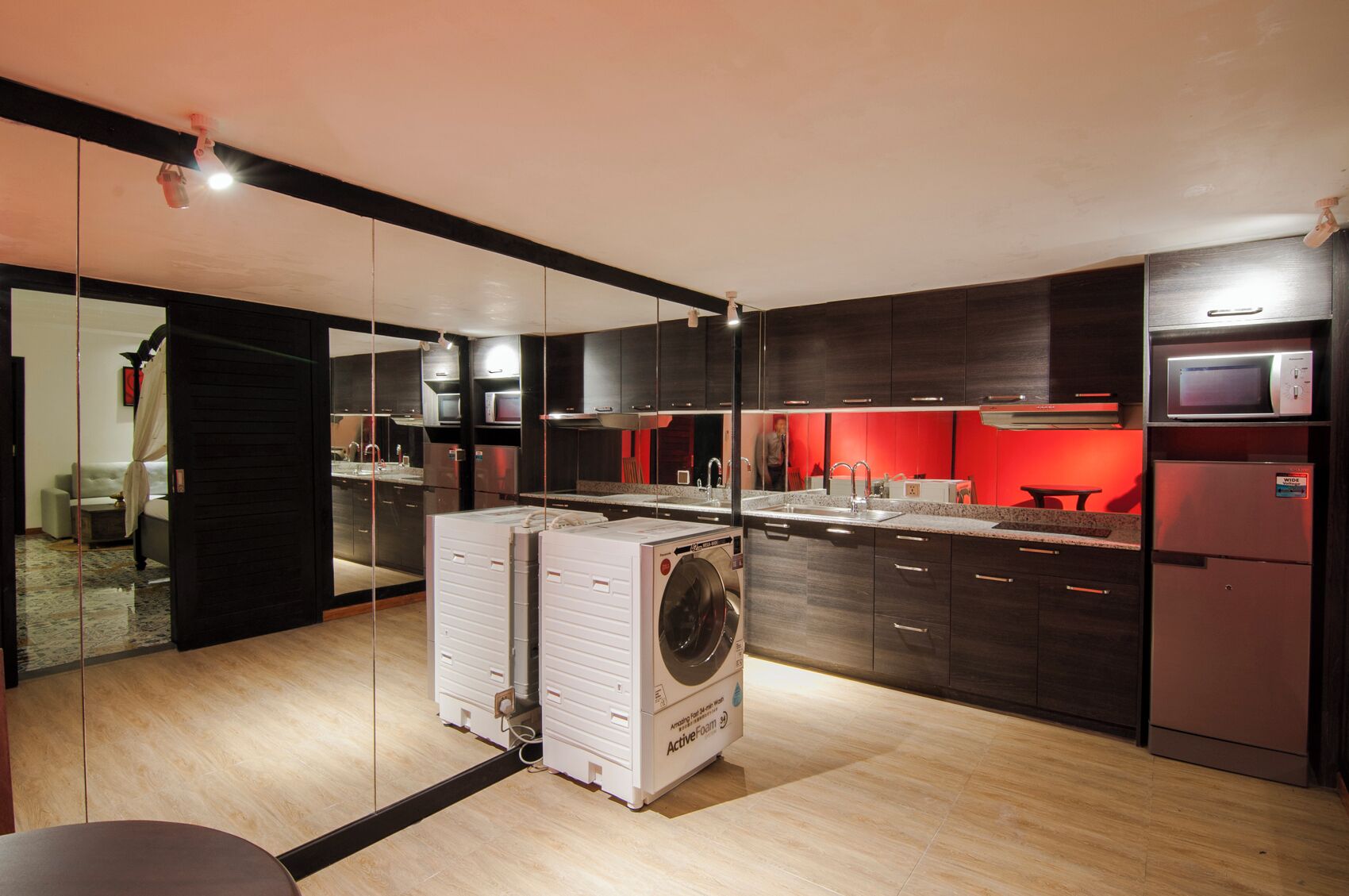 Una cocina moderna con muebles oscuros, electrodomésticos de acero inoxidable y una pared de acento roja.