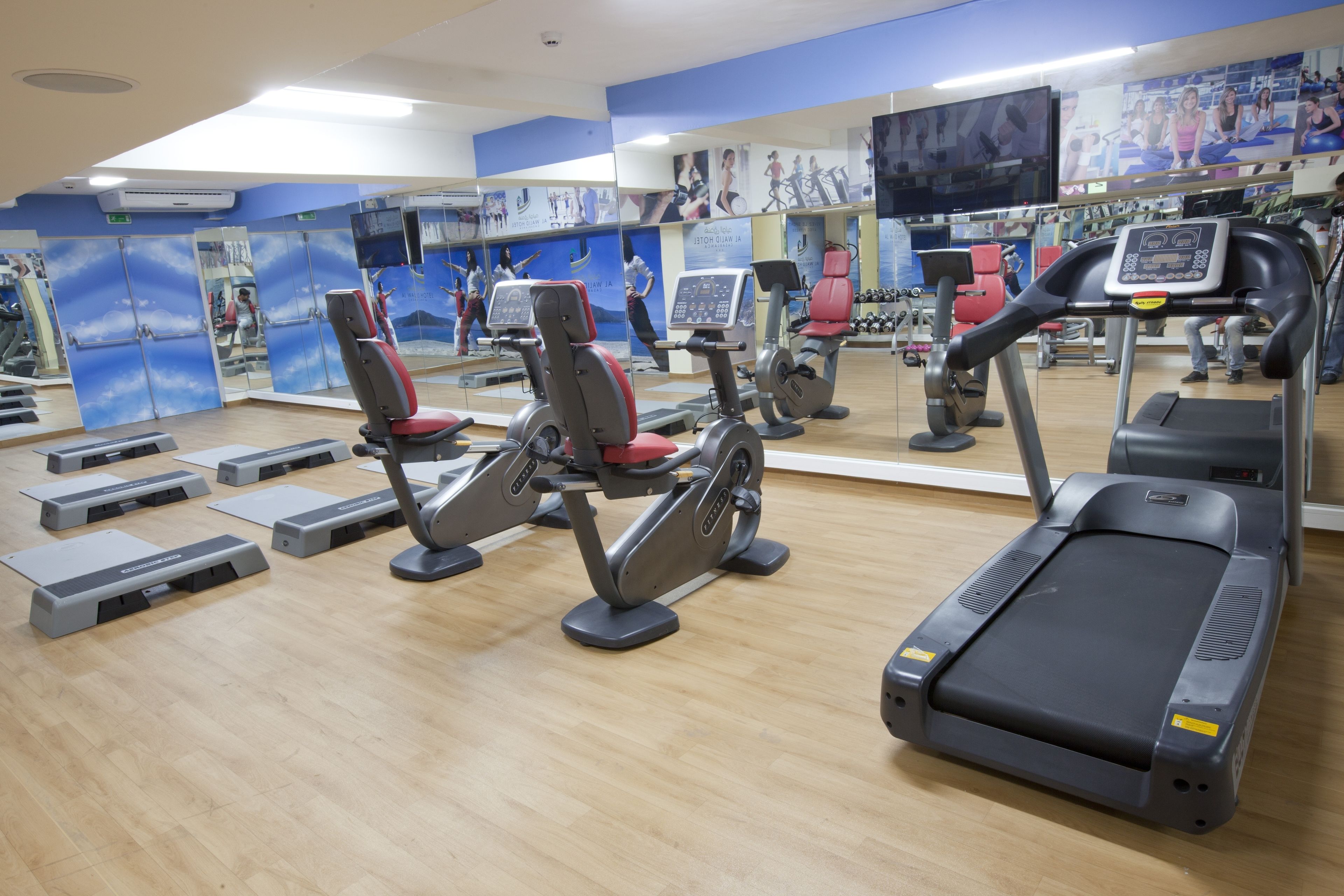 Une salle de sport équipée de matériel d’exercice, de miroirs et d’affiches motivantes.