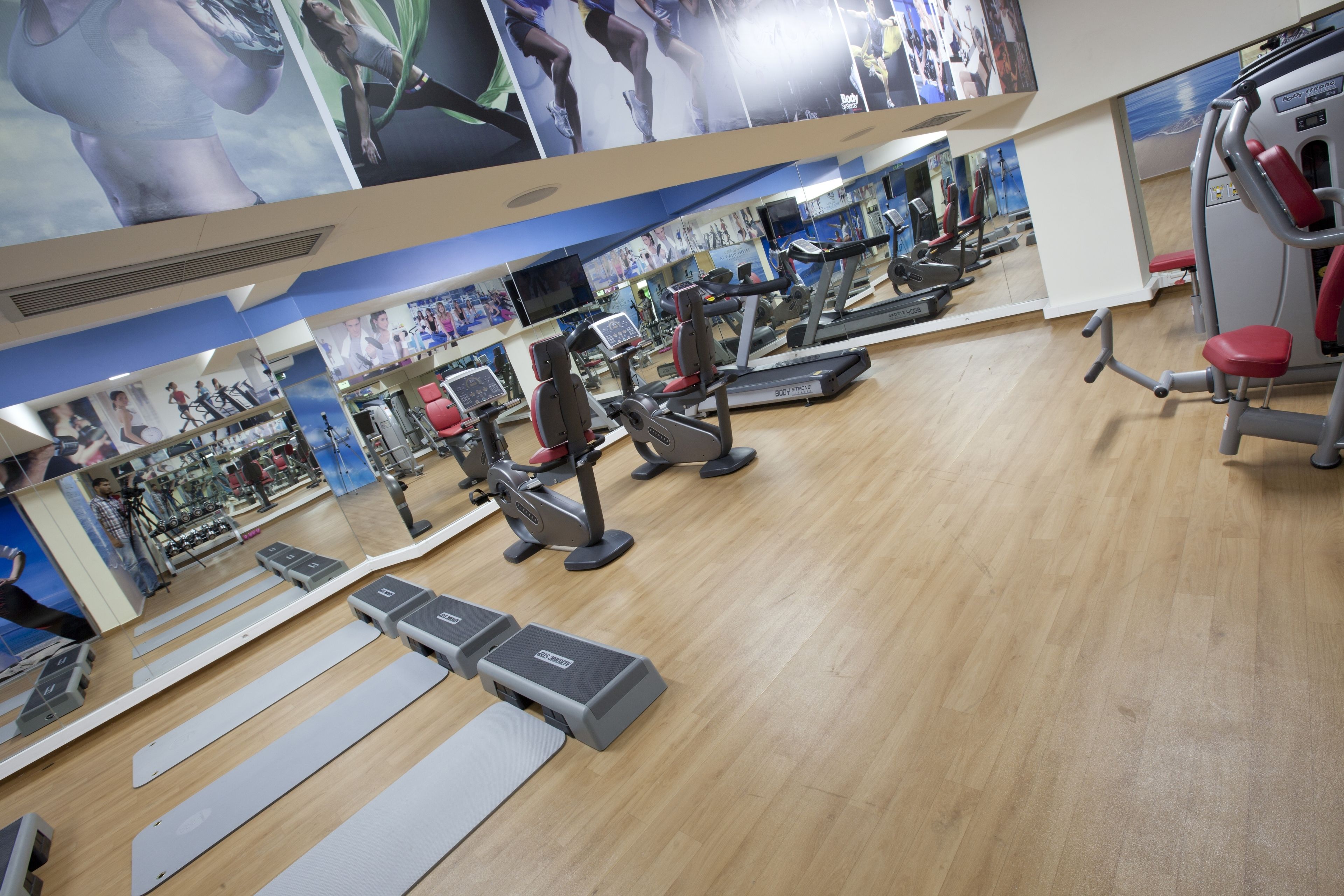 Un gimnasio con cintas de correr, máquinas de pesas y colchonetas de ejercicio.