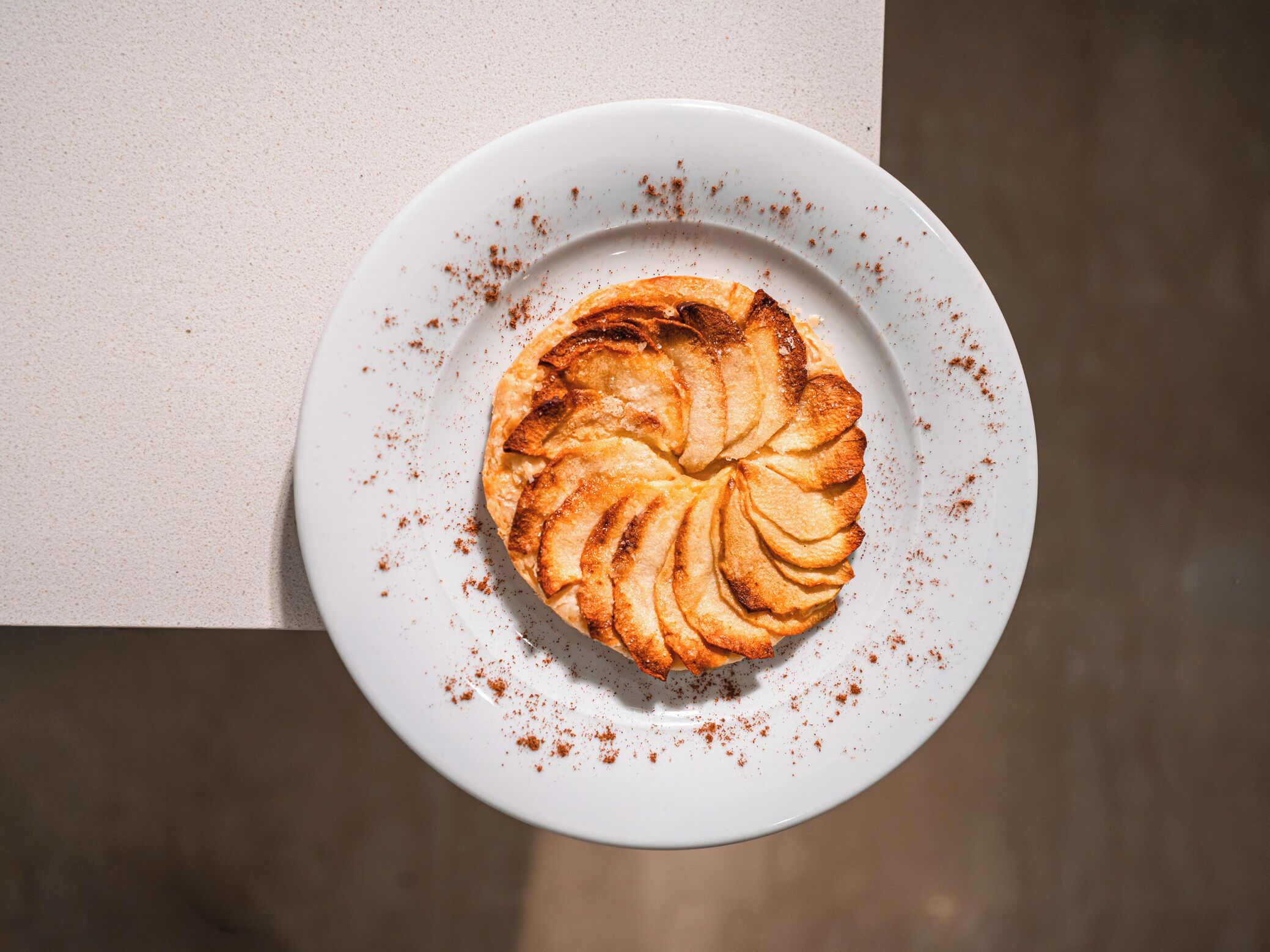Een ronde patisserie op een wit bord met een laagje kaneel.
