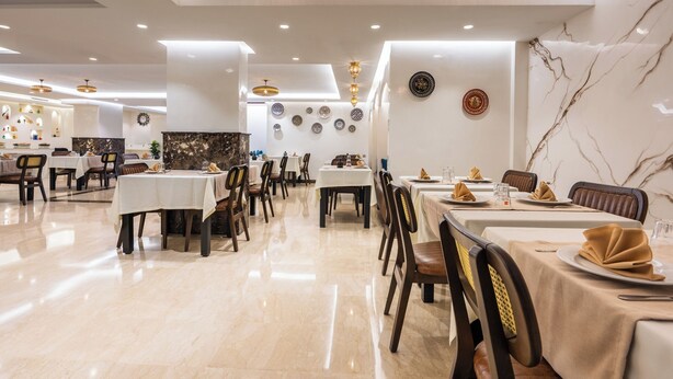 Un restaurante con varias mesas, sillas y suelo de mármol.