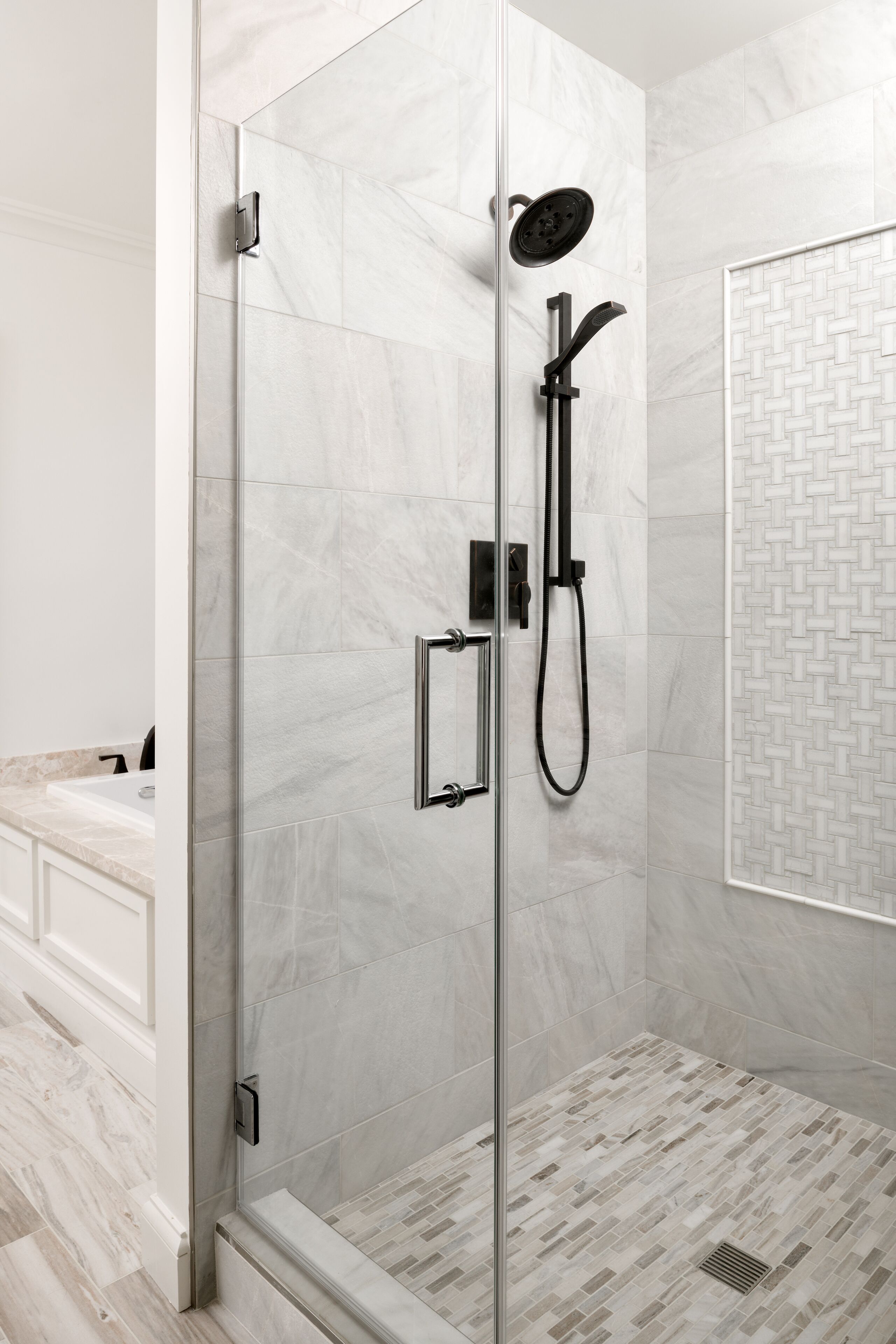 A modern shower with a glass door, a handheld showerhead, and a wall-mounted control panel.