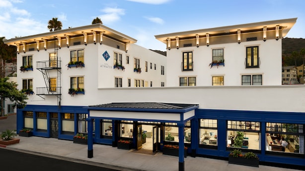 A hotel with a white facade, blue trim, and multiple windows. It features outdoor seating and a covered area. - Hotel Atwater (Avalon)