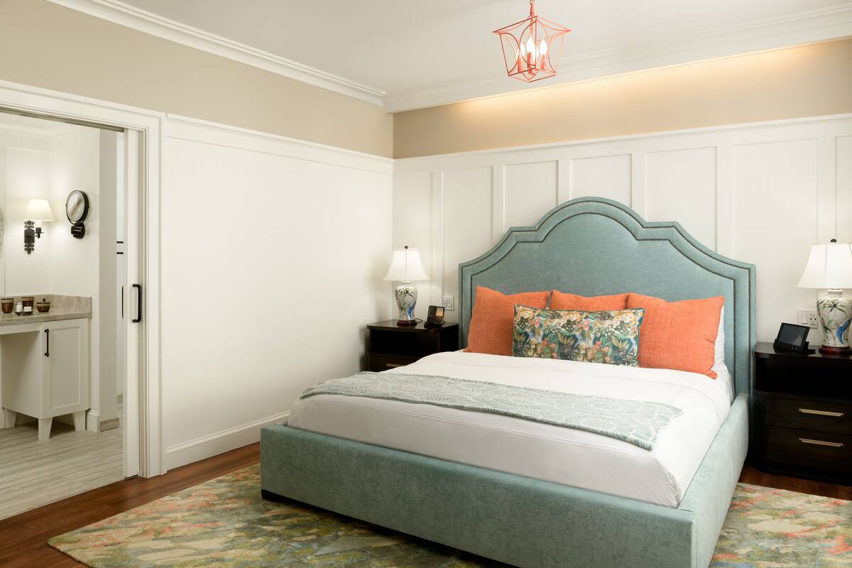 A bedroom with a bed, nightstands, a dresser, and a mirror.