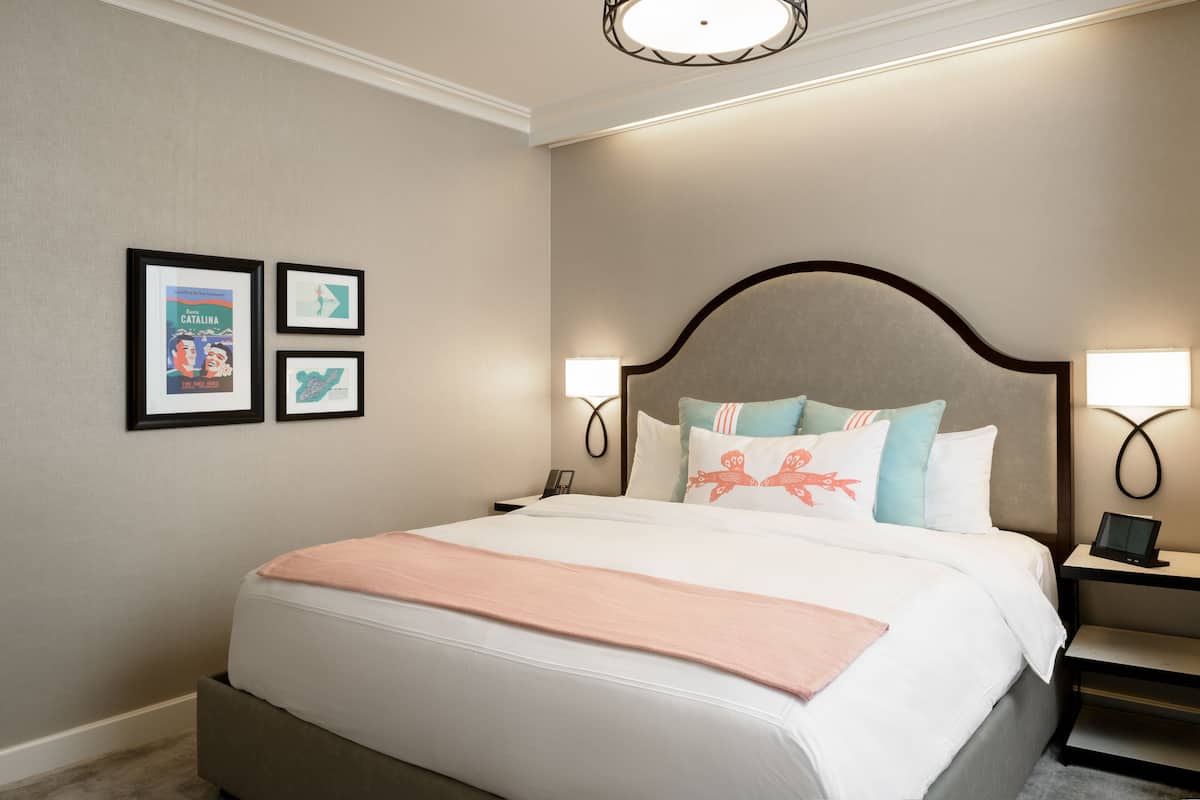 A neatly arranged hotel room with a large bed, two bedside tables, and wall-mounted lamps.