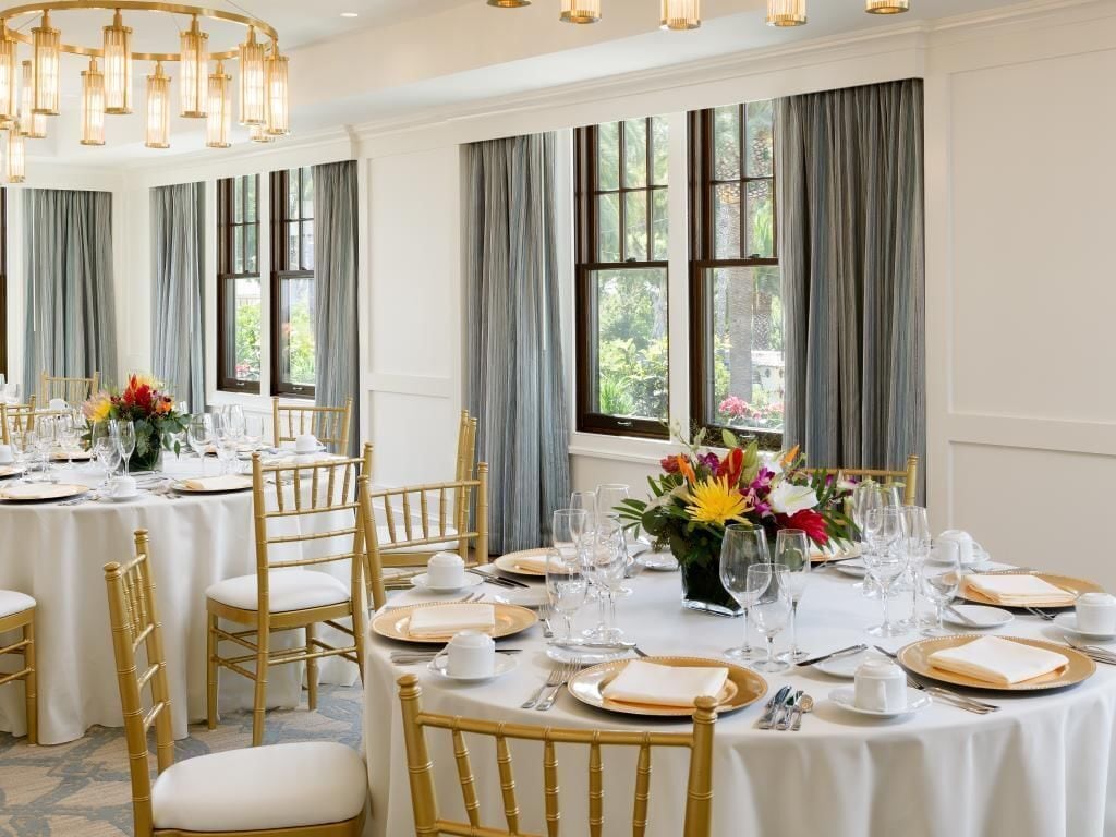 Une salle à manger avec des tables rondes, des chaises dorées et un lustre.
