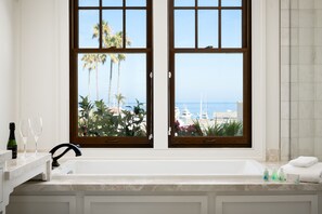 A bathroom with a large window, a bathtub, and a sink.