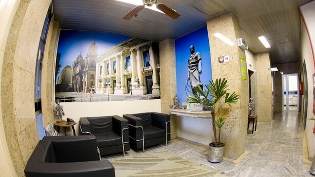 A lobby with a ceiling fan, a mural of a cityscape, a statue, and a reception desk. - Letto Hotel Porto Alegre (Porto Alegre)