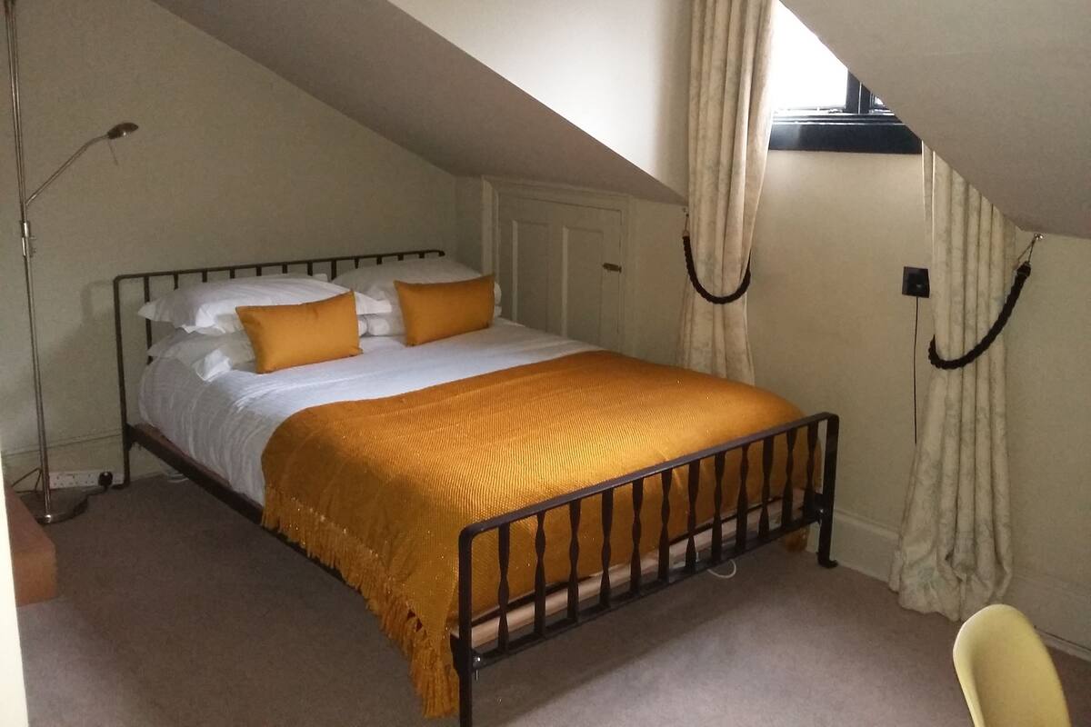 A bedroom with a bed, a chair, and a window with curtains.