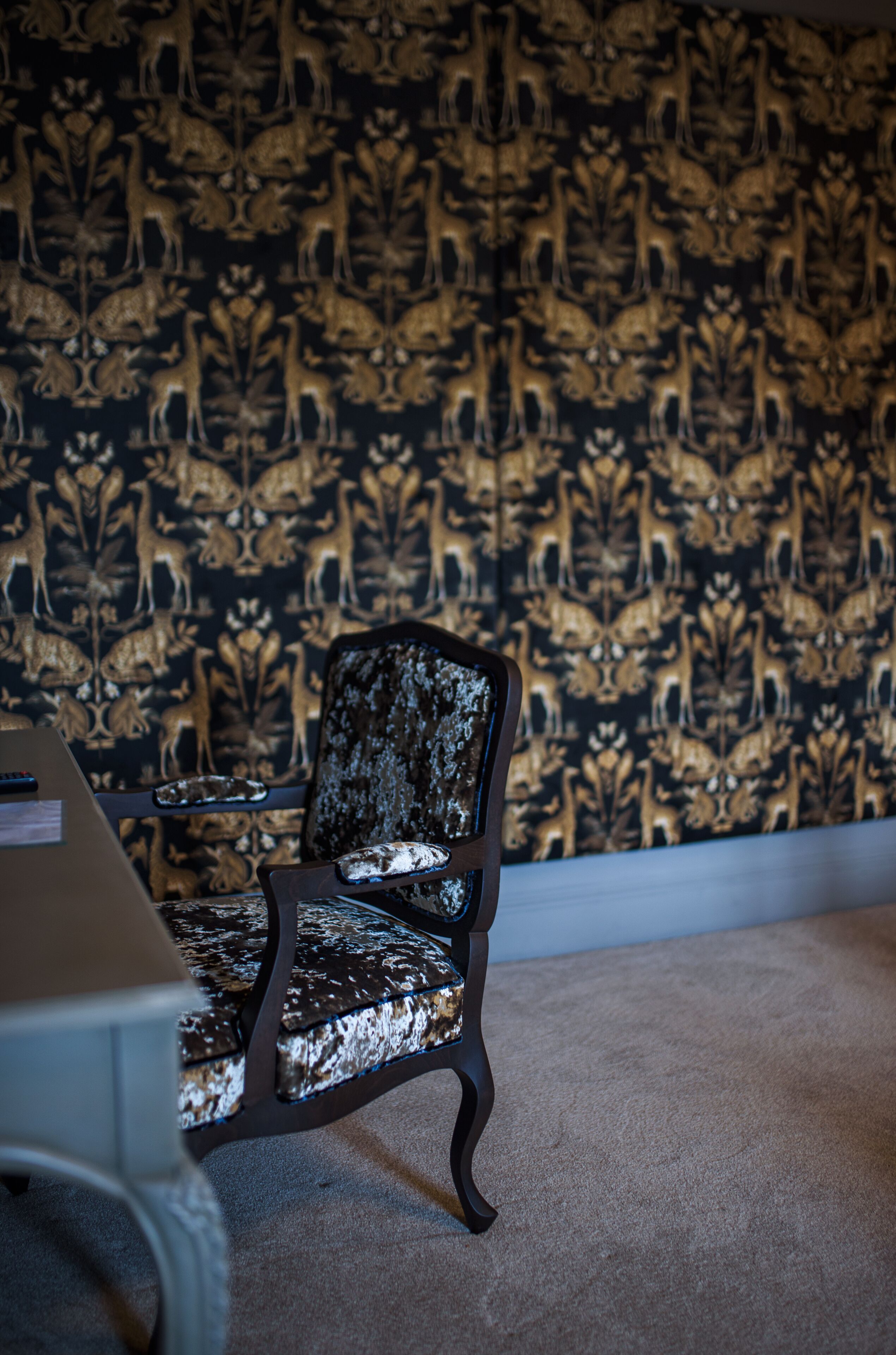 A room with a patterned wallpaper, a chair, and a table.