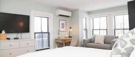 Una habitación de hotel con cama, escritorio, sofá y televisor.