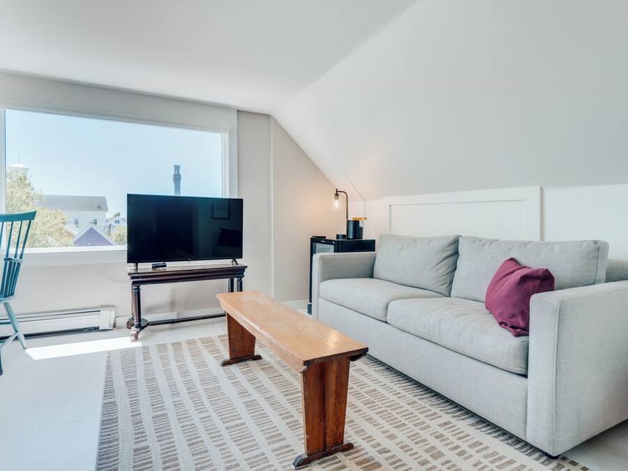 Een moderne woonkamer met een bank, een houten zitbank, een televisie en een lamp.