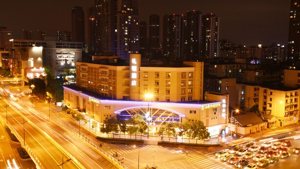 A nighttime cityscape with a prominent building featuring a large illuminated archway and signage for a spa. - Leeden Hotel Chengdu (Chengdu)