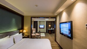A hotel room with a large bed, a desk with a computer, a television, and a small seating area. - Leeden Hotel Chengdu (Chengdu)
