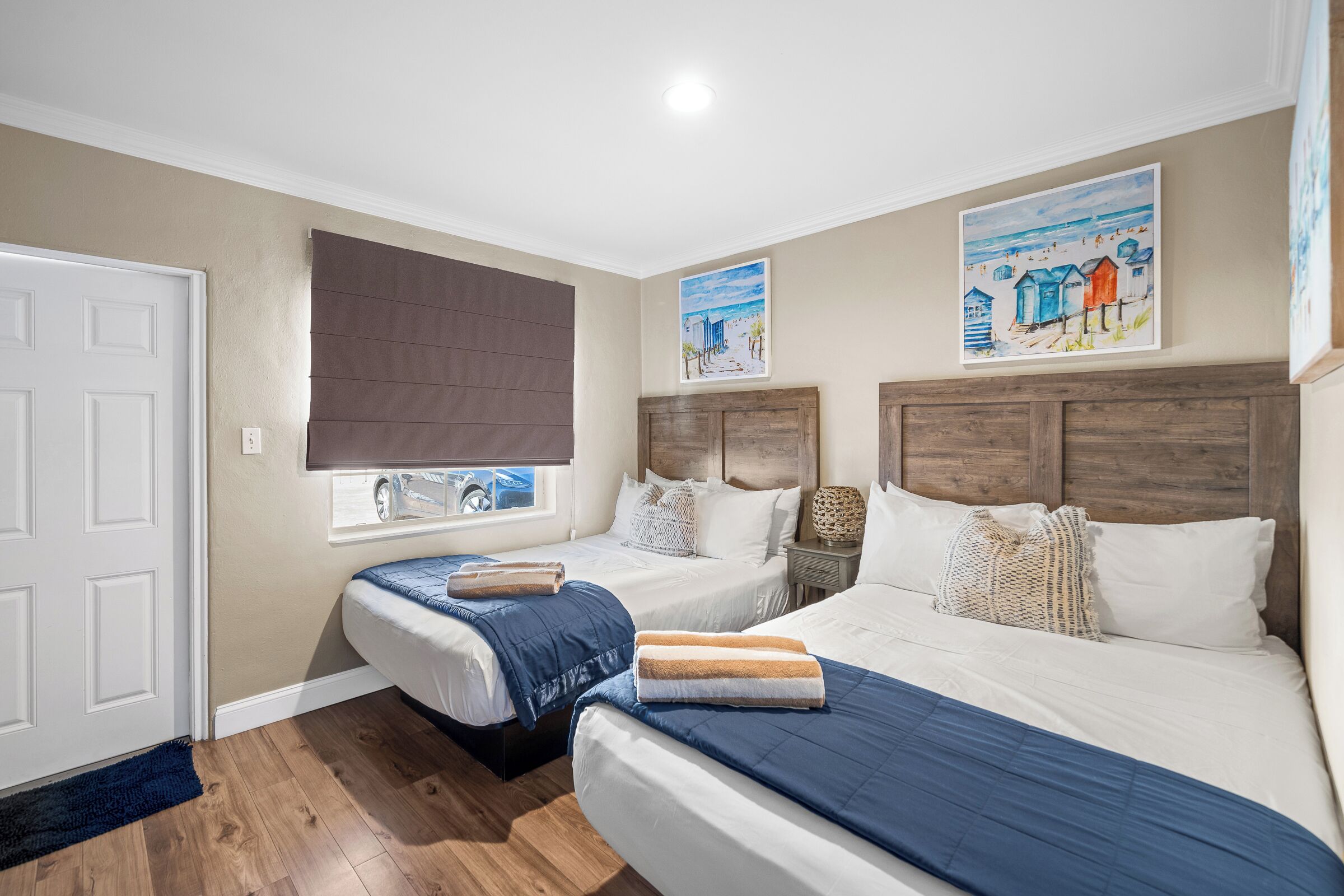 Una camera da letto con due letti singoli, un letto matrimoniale, testiere in legno, una finestra con vista e opere d'arte alle pareti.