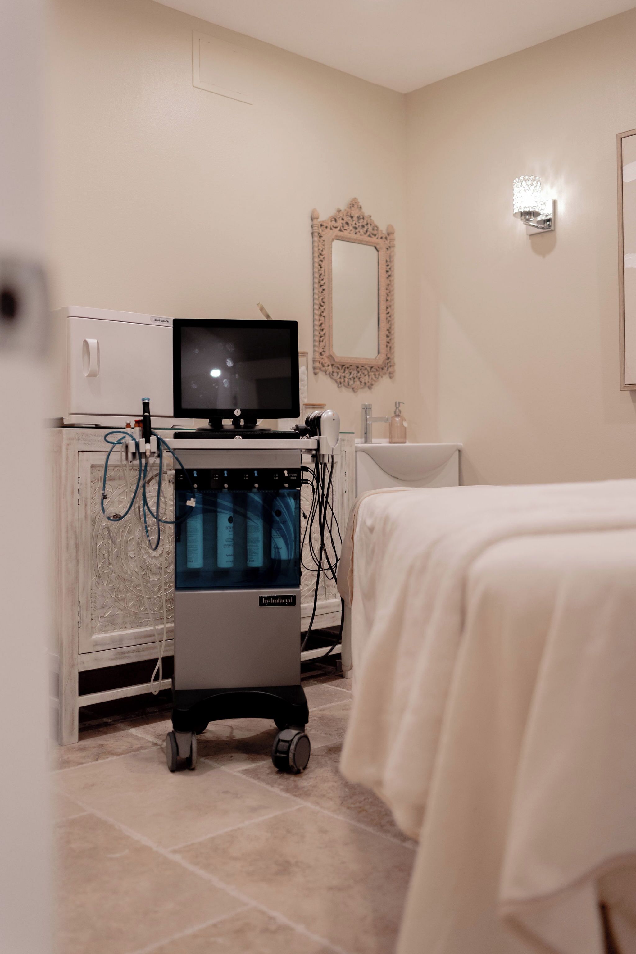 A clinical room with medical equipment, a bed, and a mirror on the wall.