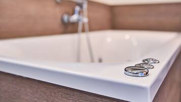 A bathroom with a white bathtub, a faucet, and a mirror.
