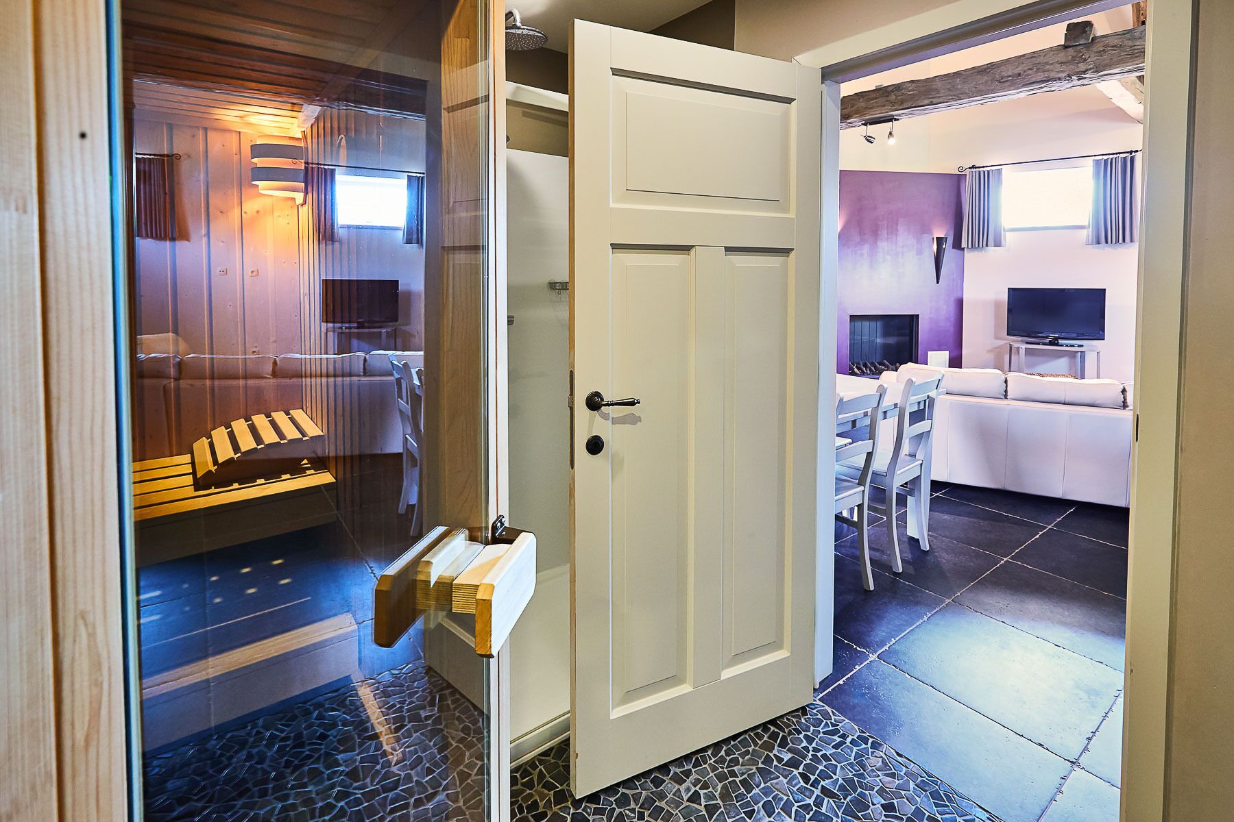 Un interno moderno con una parete in legno, una porta bianca e un'area salotto con televisore.