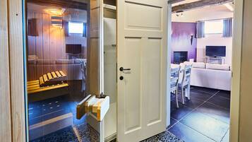 Un interno moderno con una parete in legno, una porta bianca e un'area salotto con televisore.