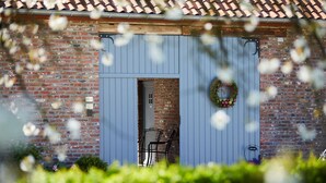 Een landelijk gebouw met een blauwe deur, een bakstenen muur en een krans op de deur.