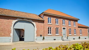 Een tweelaags gebouw van baksteen met een brede gebogen entree en een pannendak.