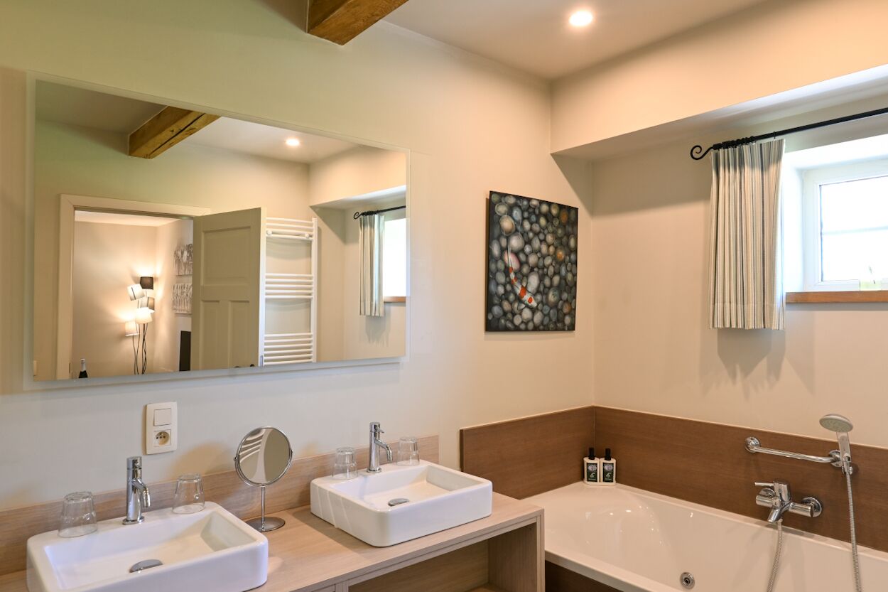 Een moderne badkamer met twee wastafels, een grote spiegel, een badkuip en een douche.