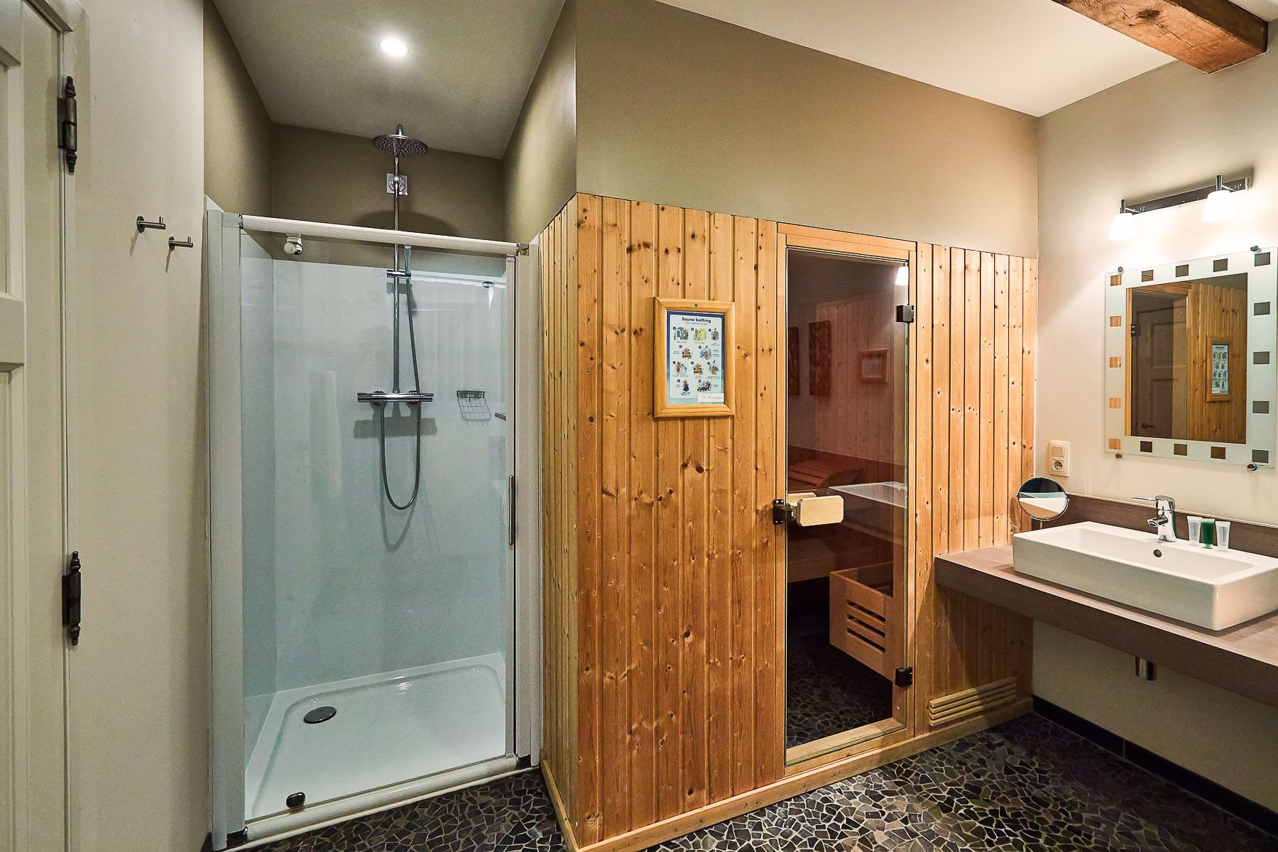 A bathroom with a glass-enclosed shower, wooden vanity, and a large mirror.