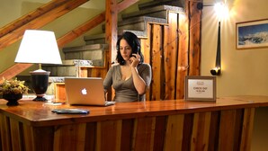 A wooden reception desk with a laptop, a framed sign, and a lamp. - Hosteria Güemes (San Carlos de Bariloche)