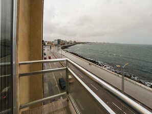 En balkon med udsigt over en kystvej og havet.