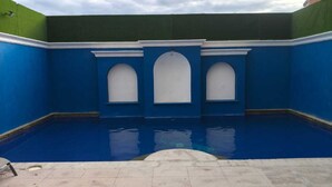 Una piscina con paredes azules y tres ventanas arqueadas.