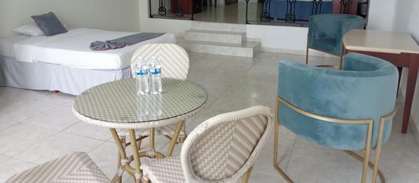 A hotel room with a bed, a round table with chairs, and a staircase leading to an outdoor area.