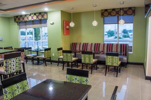 Un restaurante con paredes verdes, asientos a rayas y un letrero que dice 'Welcome'.