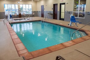 Una piscina interior con agua cristalina, una silla de salvavidas y una zona de vestuarios.