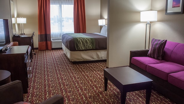 A hotel room with a bed, a desk, a sofa, and a lamp. - Comfort Inn & Suites West Artesia (Artesia)