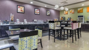 A restaurant with a counter, chairs, and tables. - Comfort Inn & Suites West Artesia (Artesia)